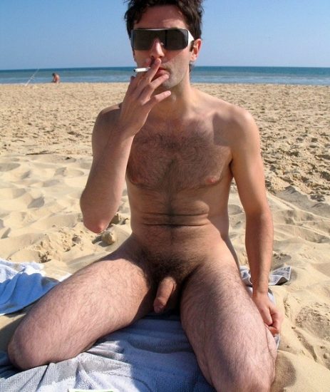 Smoking nude man on a beach